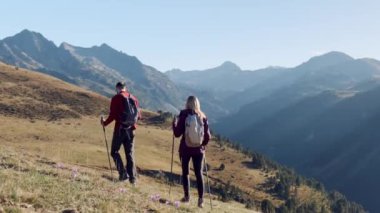 Video of two travel hikers with backpack walking while looking the landscape in the mountain. Back view.