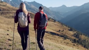 Video of two travel hikers with backpack walking while looking the landscape in the mountain. Back view.