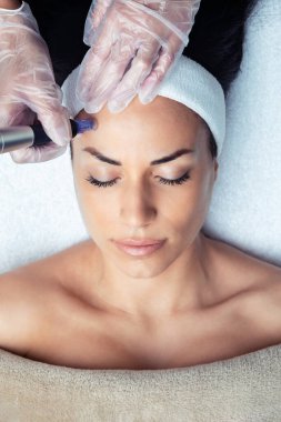 Kozmetik uzmanının spa merkezinde gençleşmek için yüzüne dermapen enjekte ettiği bir iğne..