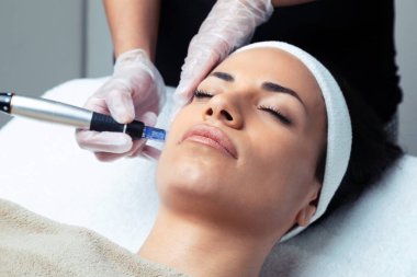 Kozmetik uzmanının spa merkezinde gençleşmek için yüzüne dermapen enjekte ettiği bir iğne..