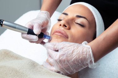 Shot of cosmetologist making mesotherapy injection with dermapen on face for rejuvenation on the spa center. clipart