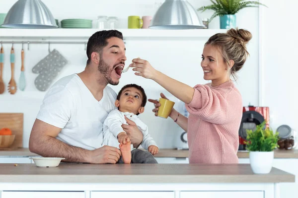 Tiro Mãe Muito Jovem Alimentando Seu Marido Enquanto Seu Bebê — Fotografia de Stock