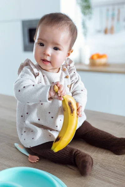 Shot Cute Little Girl Looking Side Holding Banana While Sitting — Stock Photo, Image