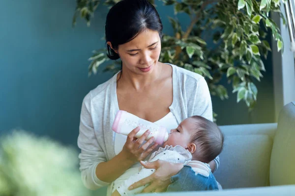 Shot Glad Ung Mor Fodrer Sin Baby Datter Med Fodringsflaske - Stock-foto