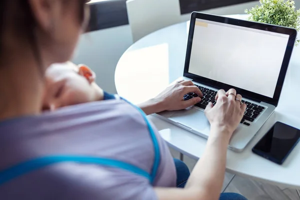 Shot Pretty Young Mother Her Baby Sling Working Laptop Home — Stock fotografie