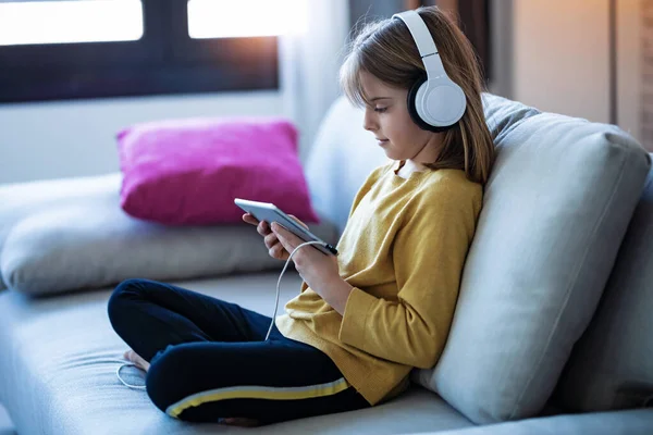 소파에 앉아서 헤드폰 디지탈 태블릿으로 음악을 소녀의 — 스톡 사진