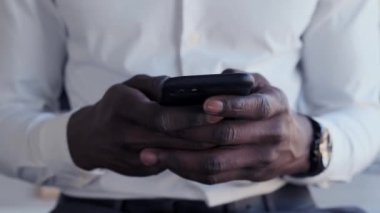 Ofiste kalırken iş adamının cep telefonuyla mesaj gönderme görüntüsü.
