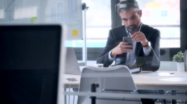 Yakışıklı iş adamının ofiste otururken akıllı telefonuyla mesaj gönderdiği bir video..