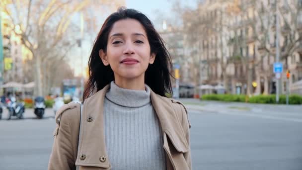 通りに立っている間にカメラを見ているかなり若い女性のビデオ 背景には 街の交通 — ストック動画