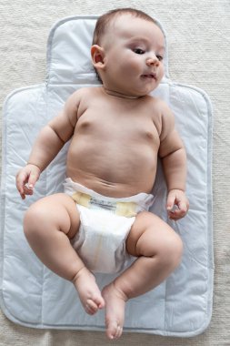 Mutlu bir bebeğin evde yatakta yatarken yan tarafına bakması..