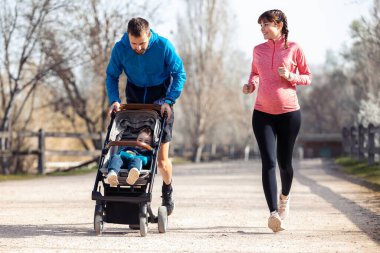 Küçük oğluyla dışarıda eğlenirken koşan genç bir çiftin fotoğrafı..