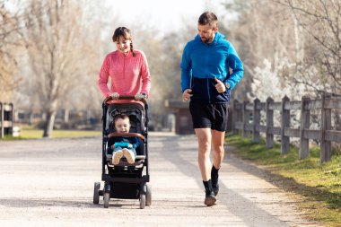 Küçük oğluyla dışarıda eğlenirken koşan genç bir çiftin fotoğrafı..