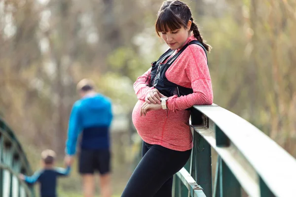 Skud Gravid Ung Kvinde Ved Hjælp Hendes Smartwatch Mens Hun - Stock-foto