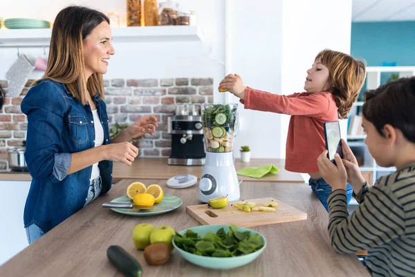 Tiro Menino Ajudando Sua Mãe Preparar Suco Desintoxicação Com Liquidificador — Fotografia de Stock