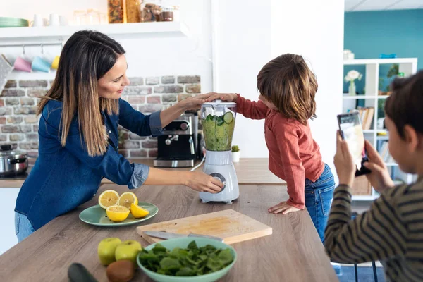 Tiro Menino Ajudando Sua Mãe Preparar Suco Desintoxicação Com Liquidificador — Fotografia de Stock