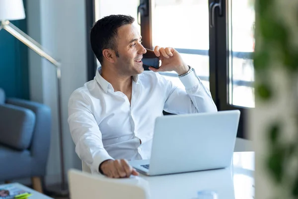 Tiro Empresário Bonito Falando Telefone Celular Enquanto Trabalhava Com Laptop — Fotografia de Stock
