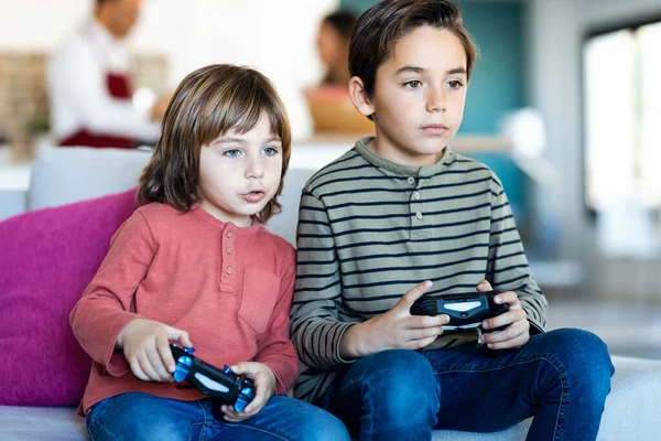Tiro Dois Irmãos Agradáveis Jogando Videogames Enquanto Sentados Sofá Casa — Fotografia de Stock