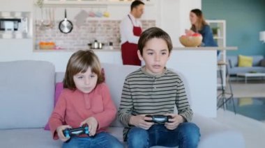 Evdeki kanepede oturmuş video oyunu oynayan iki iyi kardeşin videosu..
