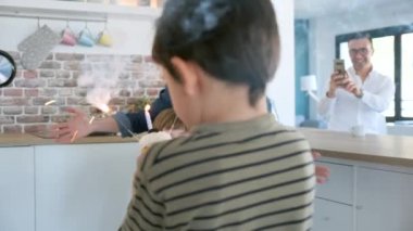 Komik çocuğun annesiyle doğum günü pastasının mumlarını üflerken videosu. Kardeşi evde tutarken..