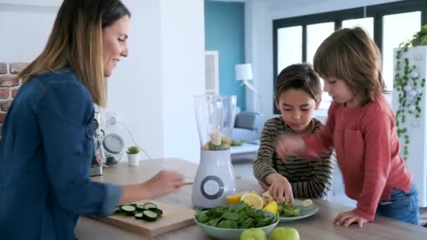 Видео Двух Мальчиков Помогающих Матери Приготовить Детоксикационный Сок Блендером Кухне — стоковое видео