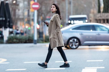 Karşıdan karşıya geçen genç ve güzel bir kadının kablosuz kulaklıkla müzik dinlerken çekilmesi..