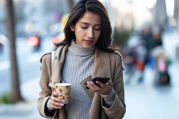Sokakta Elinde Bir Fincan Kahve Tutarken Akıllı Telefonunu Kullanan Güzel — Stok fotoğraf