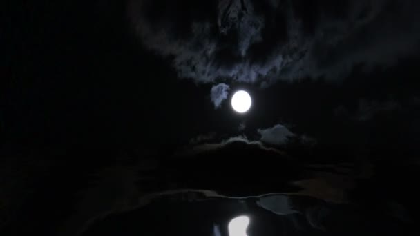 Vollmond über dem Wasser in einer bewölkten Nacht — Stockvideo