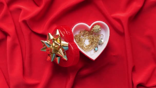 Close up van sieraden in hartvormige doos op rood satijn — Stockvideo