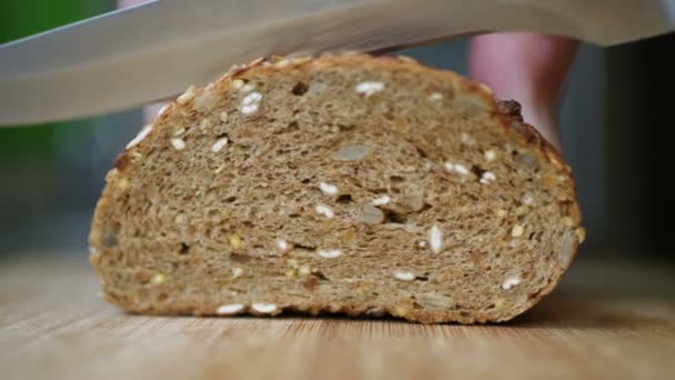 Trancher du pain de grains entiers sur une table en bois — Video