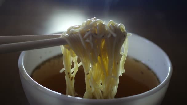 Primer plano de fideos instantáneos ramen amarillo en palillos chinos — Vídeo de stock