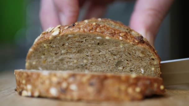 Rebanando pan de grano entero en una mesa de madera — Vídeo de stock