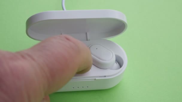 Крупним планом бездротові навушники заряджаються на зеленому екрані — стокове відео