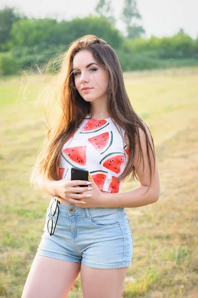 Portrait of a young beautiful woman in a park at sunset — Stock Photo, Image