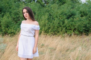 Beyaz elbiseli bir parkta güzel bir genç kız portresi