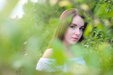 Beyaz elbiseli bir parkta güzel bir genç kız portresi