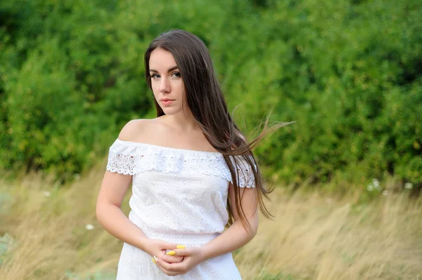 Retrato de uma jovem menina bonita em um parque em vestido branco — Fotografia de Stock