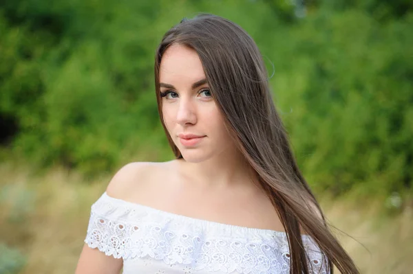 一个年轻漂亮的女孩在一个公园里白色连衣裙的肖像 — 图库照片