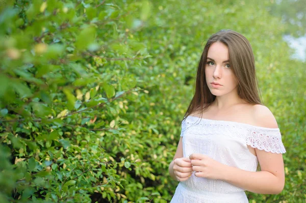 Retrato de uma jovem menina bonita em um parque em vestido branco — Fotografia de Stock