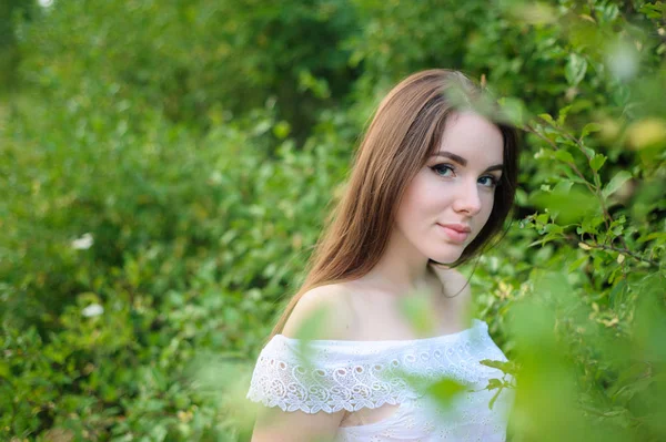 Retrato de uma jovem menina bonita em um parque em vestido branco — Fotografia de Stock