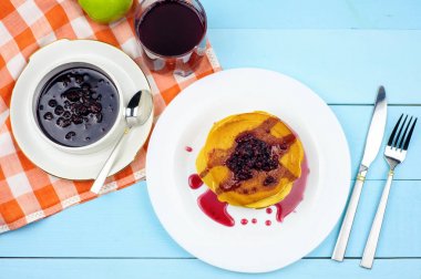 Ahududu reçeli ve mavi bir arka plan üzerinde üzüm suyu ile Pancakes