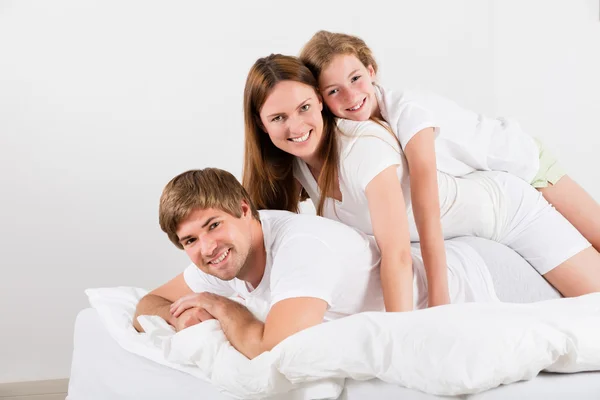 Família feliz deitada em cima uma da outra — Fotografia de Stock