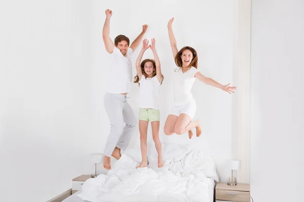 Familia saltando en la cama juntos — Foto de Stock