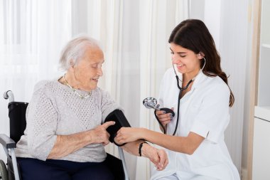 Female Doctor Checking Blood Pressure Of Senior Woman clipart