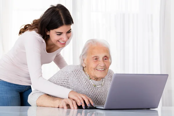 Duas mulheres sorridentes usando laptop — Fotografia de Stock