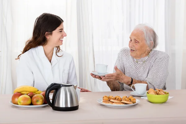 Anciana ofreciendo café a la enfermera —  Fotos de Stock