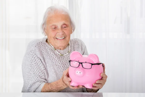 Äldre kvinna anläggning piggybank — Stockfoto