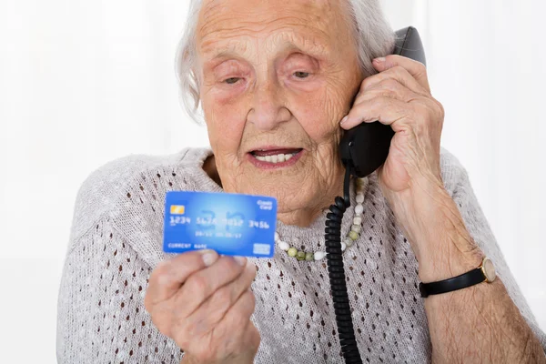 Mujer mayor con tarjeta de crédito en el teléfono — Foto de Stock