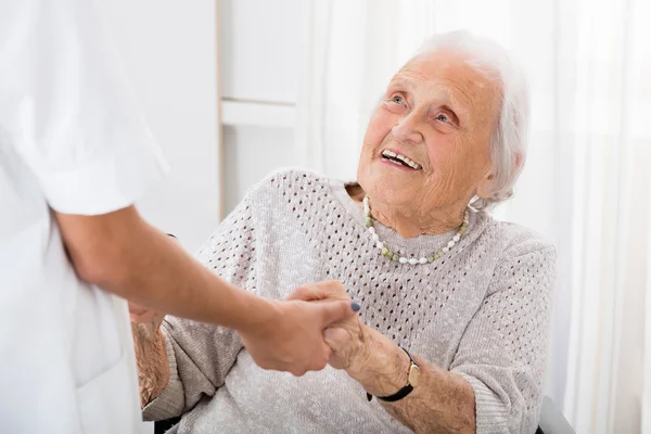 Paciente de edad avanzada que sostiene las manos del médico femenino — Foto de Stock