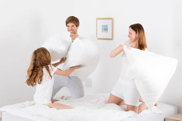 Семья с подушкой на кровати — стоковое фото