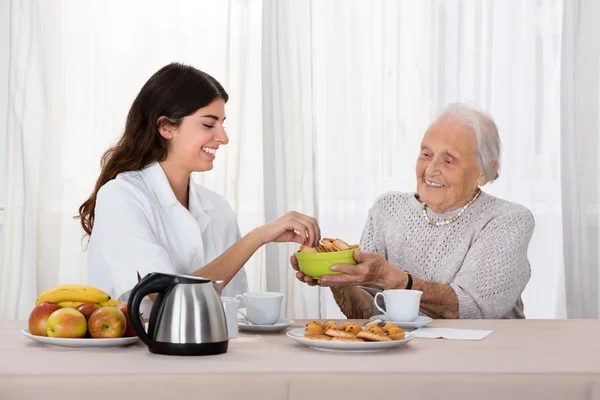 Donna anziana che offre spuntino all'infermiera — Foto Stock